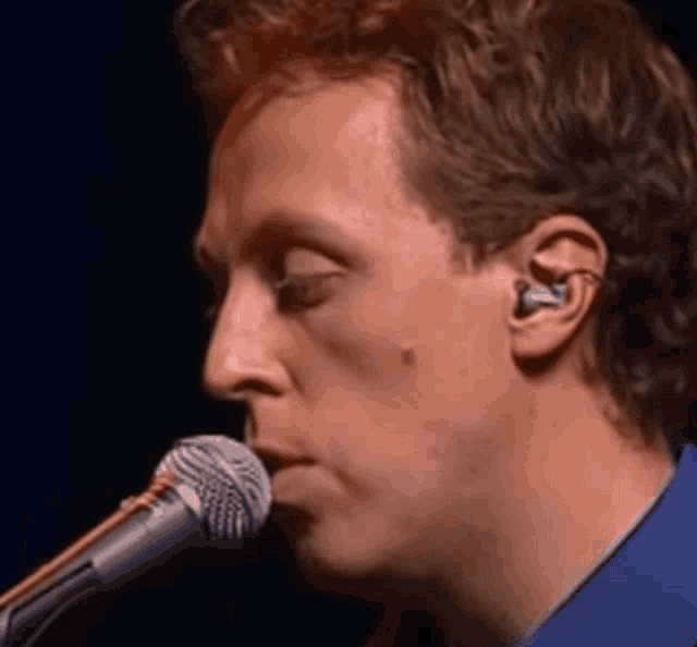 a man singing into a shure microphone with ear buds