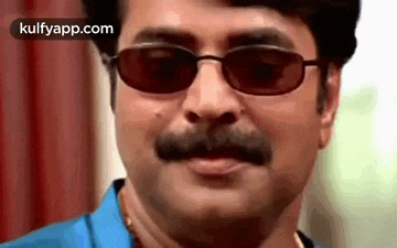 a man with a mustache is wearing sunglasses and making a funny face .