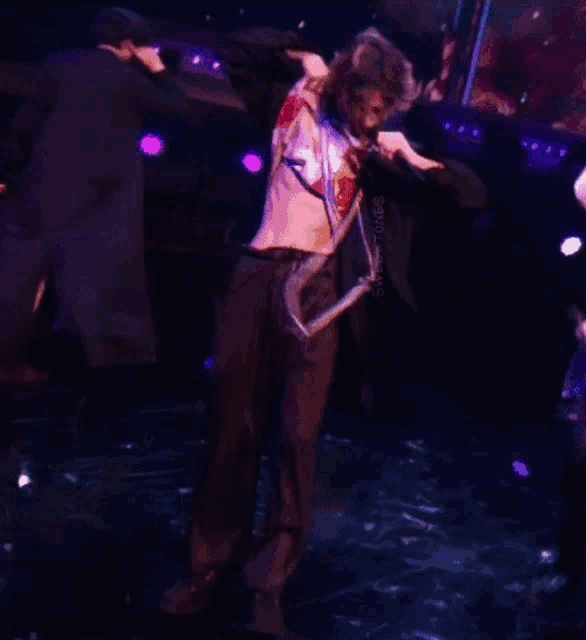 a man in a suit is dancing on a stage with a snake around his neck and the word snake is on the bottom