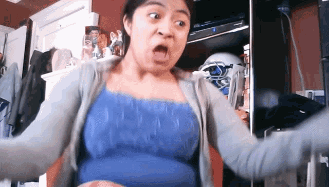 a woman in a blue tank top making a funny face with her mouth open