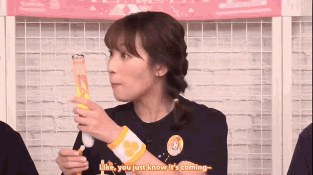 a woman in a black shirt is holding a bottle and talking to someone .