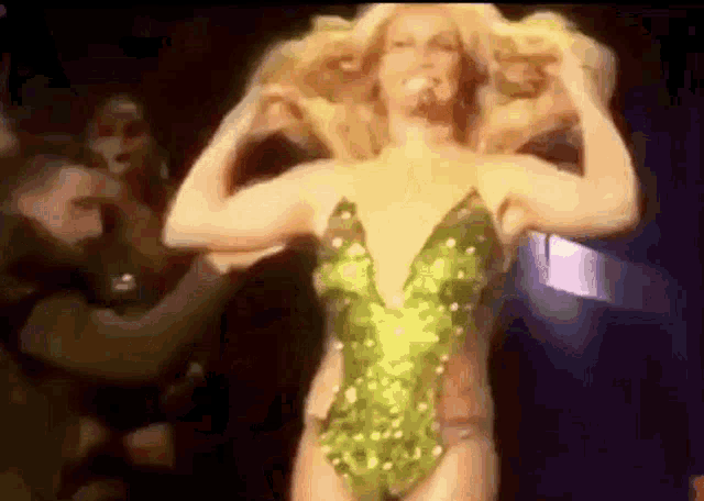 a woman in a green bodysuit is standing on a stage .