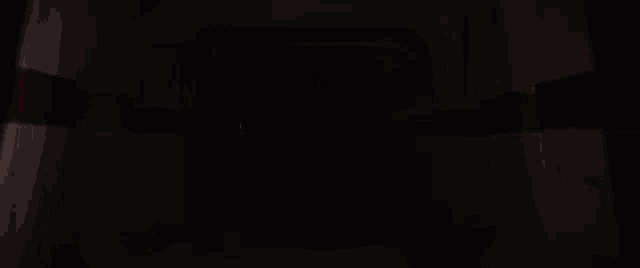 a person is holding a lightsaber in a dark room with a red light coming out of it .