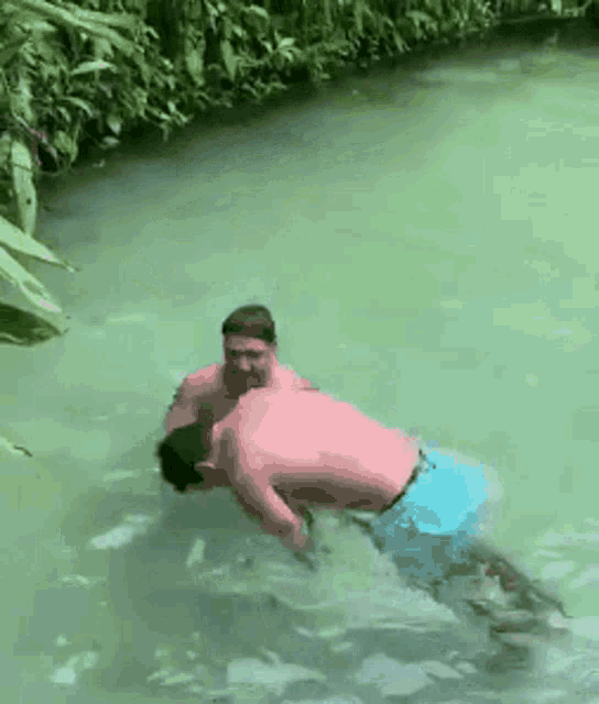 two men are swimming in a river and one is holding the other 's arm