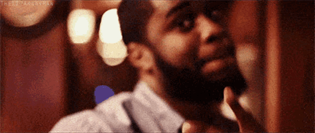 a man with a beard is shaving his beard with a razor in a blurry picture .