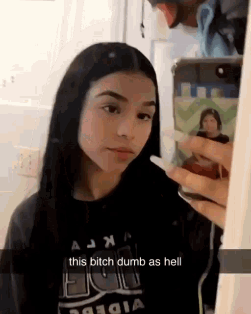 a girl is taking a selfie in front of a mirror with a cell phone .