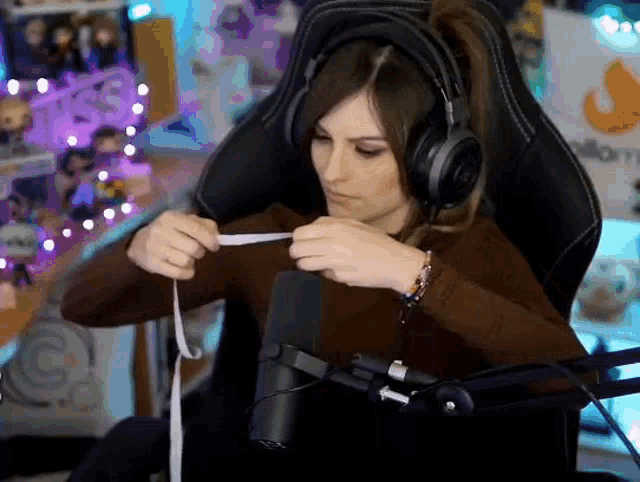 a woman wearing headphones is measuring her waist with a tape measure while sitting in a chair .