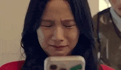 a close up of a woman crying while looking at her phone .