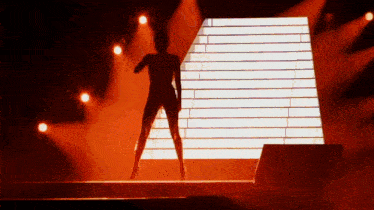 a silhouette of a woman dancing in front of a large screen