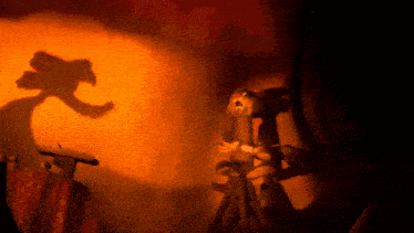 a shadow of a monster is cast on a wall behind a stuffed animal