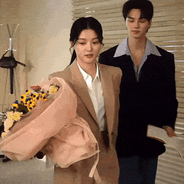 a woman in a suit holds a bouquet of flowers next to a man in a suit