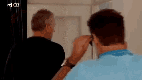 two men are standing next to each other in front of a door .