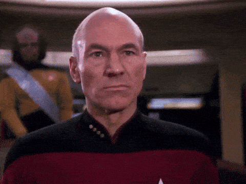 a bald man wearing a red and black uniform looks at the camera