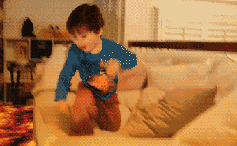 a young boy in a blue shirt is sitting on a white couch