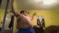 a shirtless man is dancing in a room with a picture of two men on the wall .