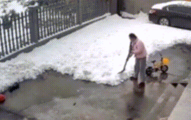 a person is shoveling snow in a driveway in front of a car