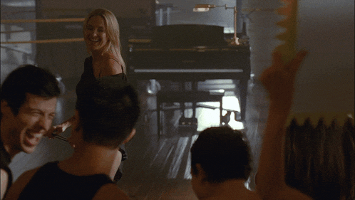 a woman stands in front of a piano in a dance studio