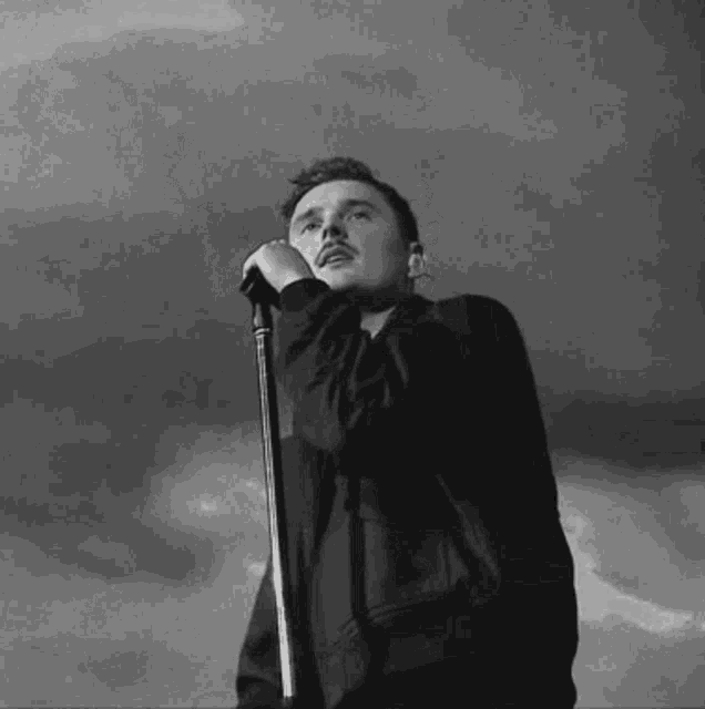 a man is singing into a microphone while looking up at the sky .