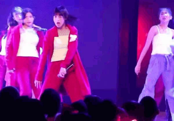 a woman in a red jacket is singing into a microphone on stage