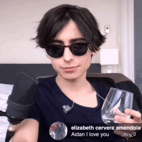 a young man wearing sunglasses is holding a glass of water