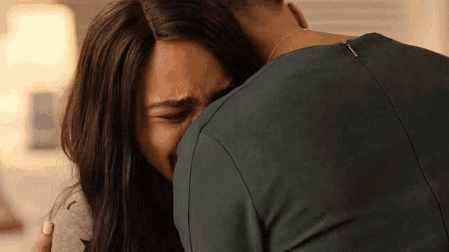 a man hugging a woman who is crying with her eyes closed