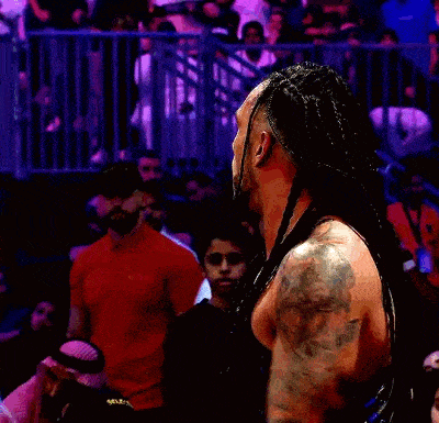 a man with dreadlocks and a tattoo on his arm is giving a thumbs up .
