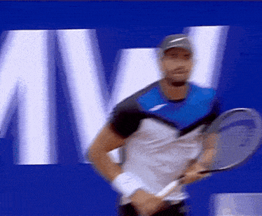 a blurry picture of a man holding a tennis racquet in front of a large letter m