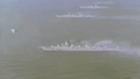 a group of military ships are floating in the water .