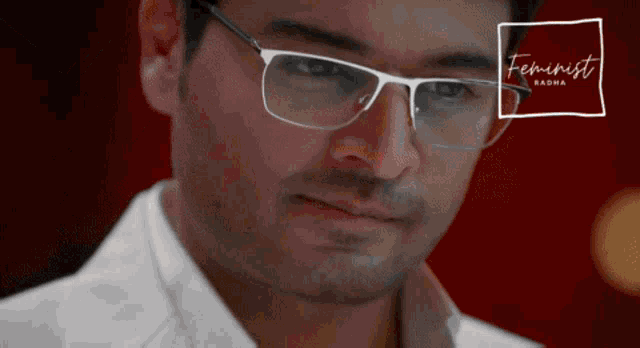 a close up of a man wearing glasses with the words feminist radha below him