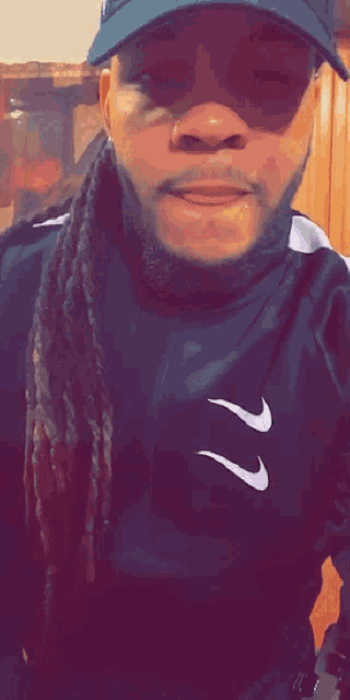 a man with dreadlocks wearing a nike shirt