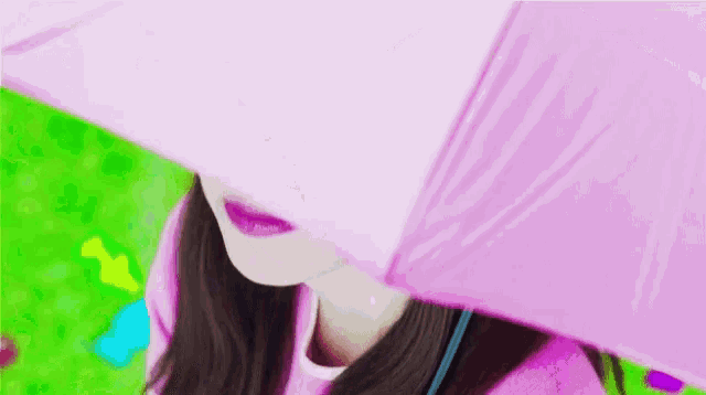 a woman covering her face with a pink umbrella .