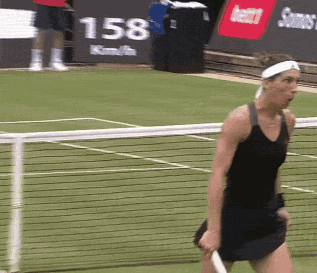 a woman is holding a tennis racquet on a tennis court with a sign that says 158 in the background