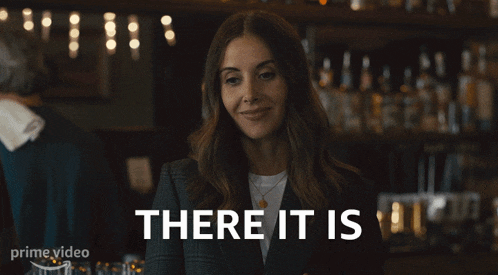 a woman in a suit is smiling with the words there it is behind her