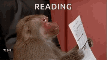 a monkey is reading a newspaper while sitting on a couch .