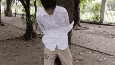 a man is tied to a tree wearing a white shirt and cool boy pants