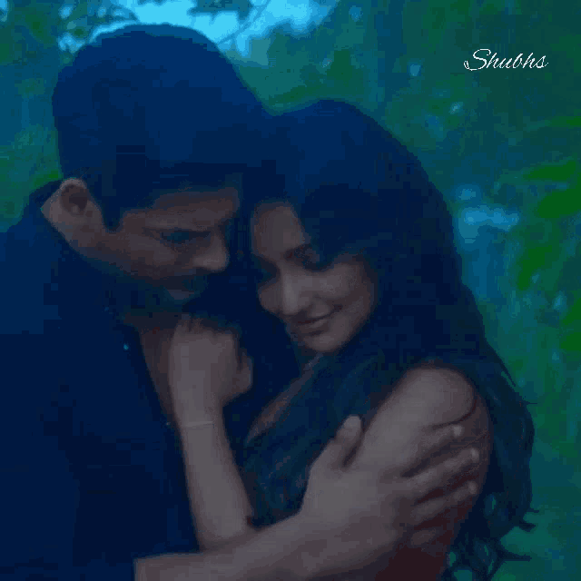 a man and a woman are hugging each other in a forest