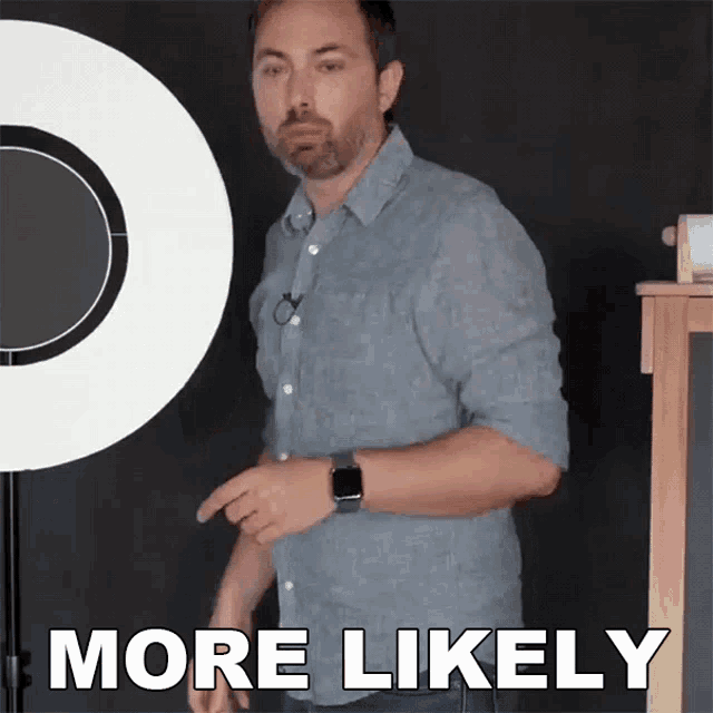 a man in a blue shirt stands in front of a sign that says more likely on it