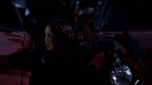 a woman standing next to a red car holding the headlight