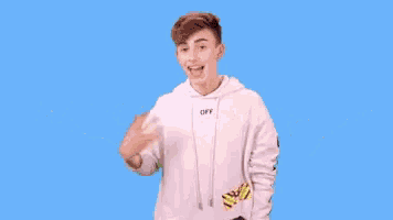 a young man is standing in front of a blue background with the words happy birthday written on it