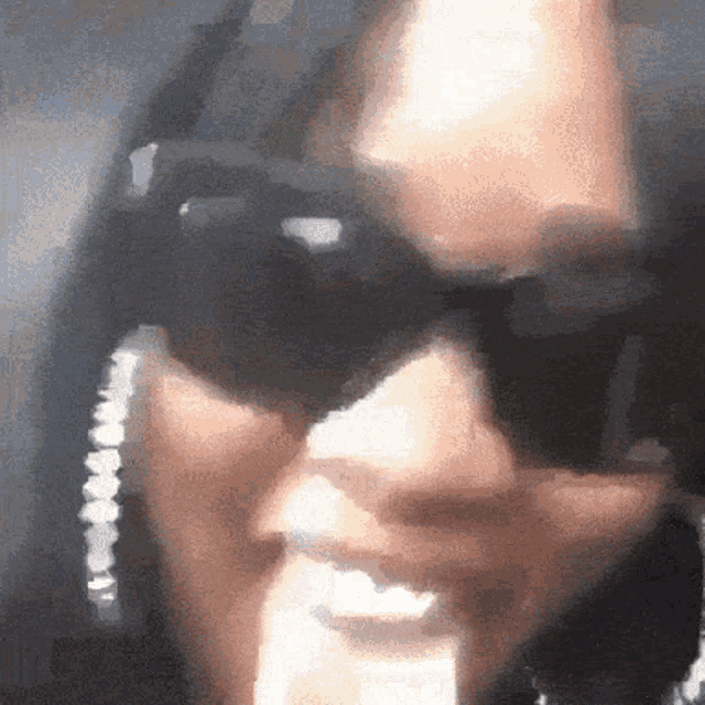 a close up of a person wearing sunglasses and a necklace
