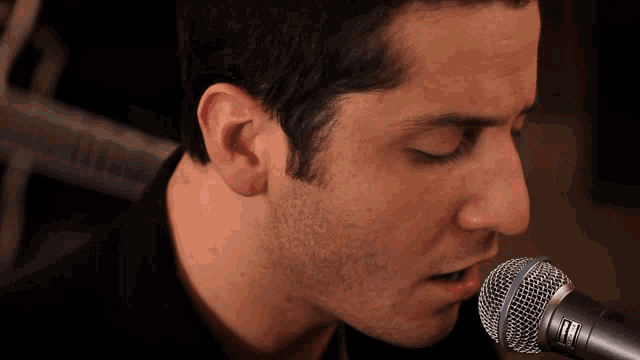 a close up of a man singing into a shure microphone