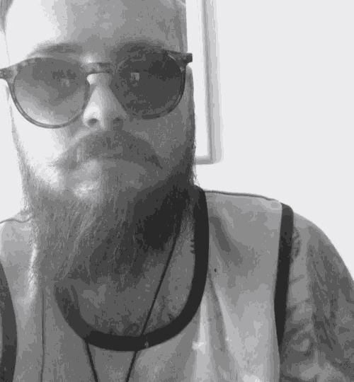 a bearded man wearing sunglasses and a tank top