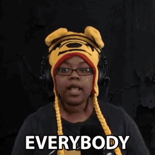 a woman wearing a tiger hat and headphones is making a funny face and saying `` everybody '' .