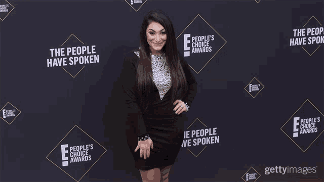 a woman is standing in front of a wall that says the people 's choice awards