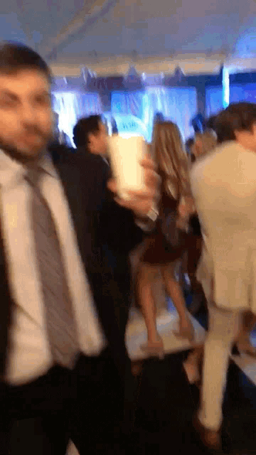 a man in a suit and tie is walking through a crowd of people at a party
