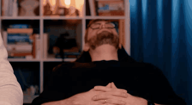 a man with a beard and glasses is laying down with his eyes closed