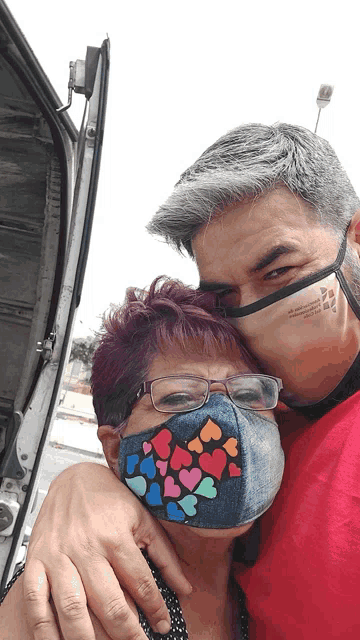 a man and woman wearing face masks with hearts on them are hugging