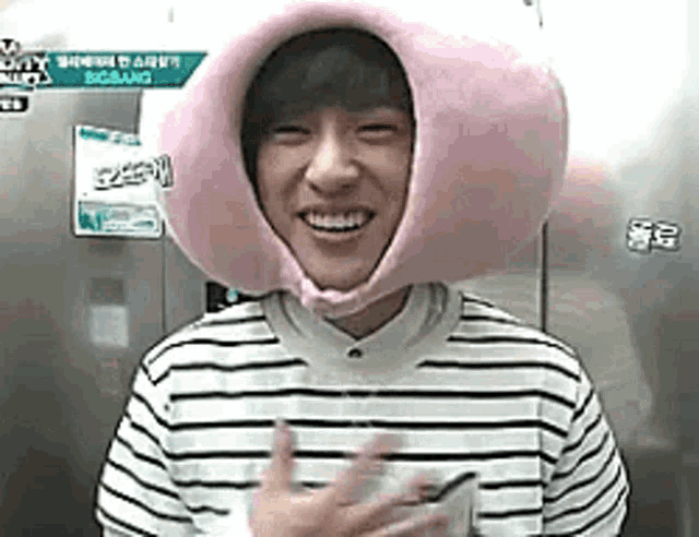 a young man wearing a pink hat and a striped shirt .