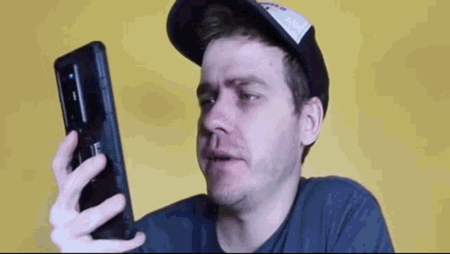 a man wearing a hat is holding a cell phone .