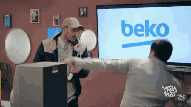 two men fighting in front of a beko television
